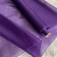 A roll of Longan Craft's Multicolor 8 Momme Organza Silk Fabric by the yard, made from pure mulberry silk, is partially unrolled to reveal its sheer, vibrant texture—ideal luxury material for making elegant dresses.
