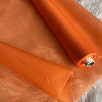 A roll of Longan Craft’s Multicolor 8 Momme Organza Silk Fabric By The Yard, made from pure mulberry silk, is unrolled on a soft white surface, showcasing its translucent texture—ideal luxury material for elegant dresses.