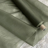 A roll of Multicolor 8 Momme Organza Silk Fabric by Longan Craft lies partially unrolled, revealing its smooth, slightly shiny pure mulberry silk texture—ideal luxury material for elegant dresses.