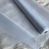 A roll of Multicolor 8 Momme Organza Silk Fabric by Longan Craft is unrolled on a white, fluffy surface. This pure mulberry silk material looks delicate and translucent—luxury fabric by the yard, ideal for elegant dresses.