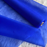 A roll of Longan Craft's Multicolor 8 Momme Organza Silk Fabric by the yard, made from pure mulberry silk, is partially unrolled on a white textured surface—luxury material perfect for elegant dresses.