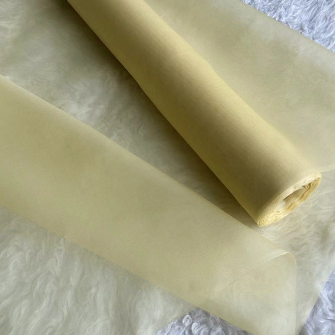 A close-up of two rolls of Longan Craft’s Multicolor 8 Momme Organza Silk Fabric by the yard, made from pure mulberry silk, their translucent sheen and smoothness ideal for luxury dresses and reminiscent of elegant evening gowns.