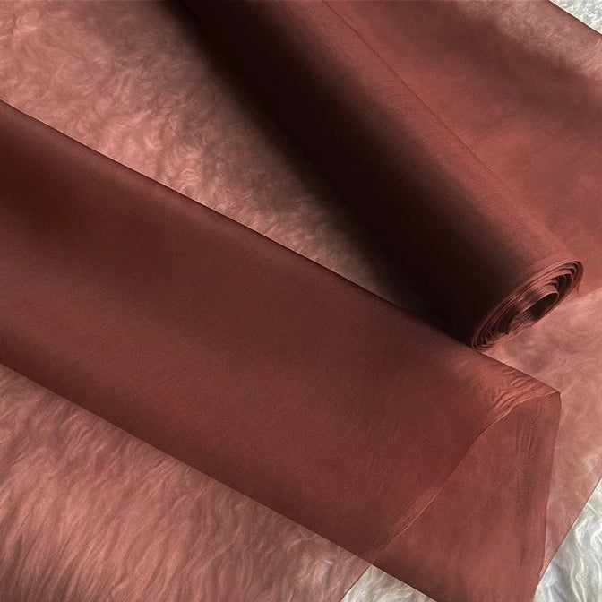 Two rolls of Multicolor 8 Momme Organza Silk Fabric by Longan Craft, made from pure mulberry silk, are displayed on a flat surface, showcasing their smooth, translucent texture and luxurious sheen—perfect for elegant dresses.