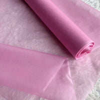 A roll of Longan Craft Multicolor 8 Momme Organza Silk Fabric by the yard, made from pure Mulberry silk for luxury dresses, is partially unrolled to showcase its delicate, translucent texture on a light surface.