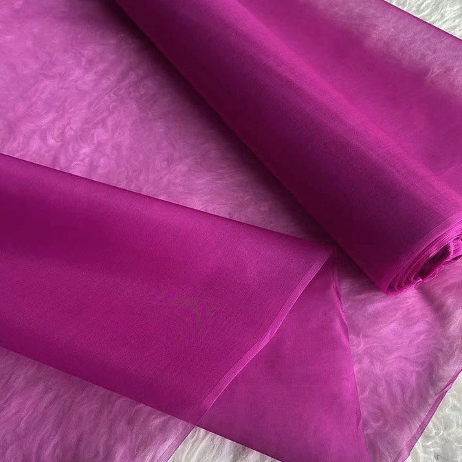 A close-up of Longan Craft’s Multicolor 8 Momme Organza Silk Fabric By The Yard shows its vibrant, sheer, and lightweight pure mulberry silk texture, partially unrolled on a flat surface—luxury silk for dresses.