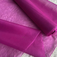 A close-up of Longan Craft’s Multicolor 8 Momme Organza Silk Fabric By The Yard shows its vibrant, sheer, and lightweight pure mulberry silk texture, partially unrolled on a flat surface—luxury silk for dresses.