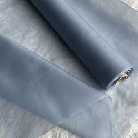 Two yards of Longan Craft’s Multicolor 8 Momme Organza Silk Fabric by the Yard, made from pure mulberry silk for luxury dresses, are partially unrolled on a textured white surface, showcasing their smooth, translucent, and delicate quality.