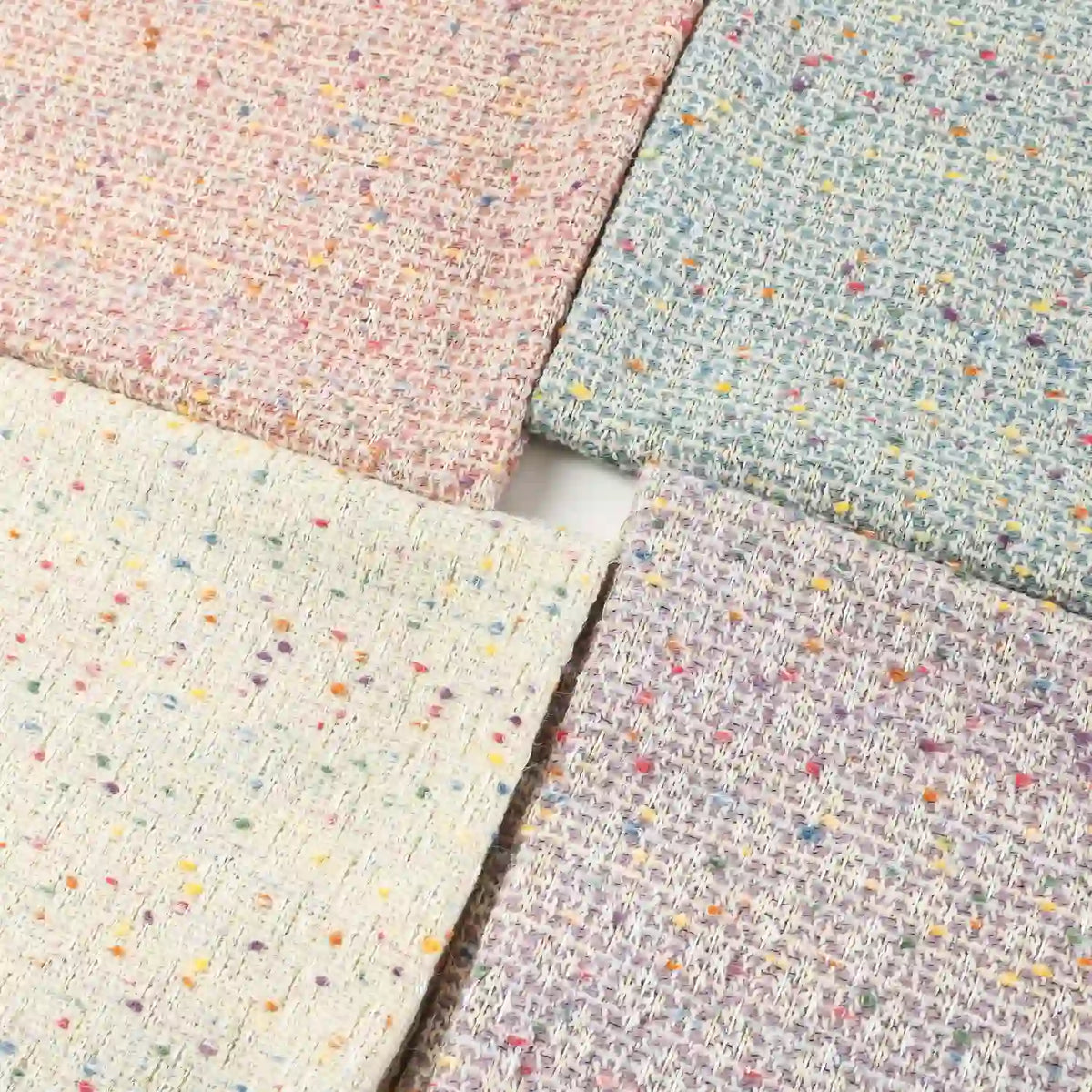 Four swatches of Longan Craft’s Multicolor Dot Bouclé Tweed Fabric By The Yard—a heavyweight jacquard wool blend suiting material—are displayed in pastel pink, blue, cream, and lavender shades. Each features colorful speckles reminiscent of classic multicolor bouclé tweed and are arranged in a square on a white background.