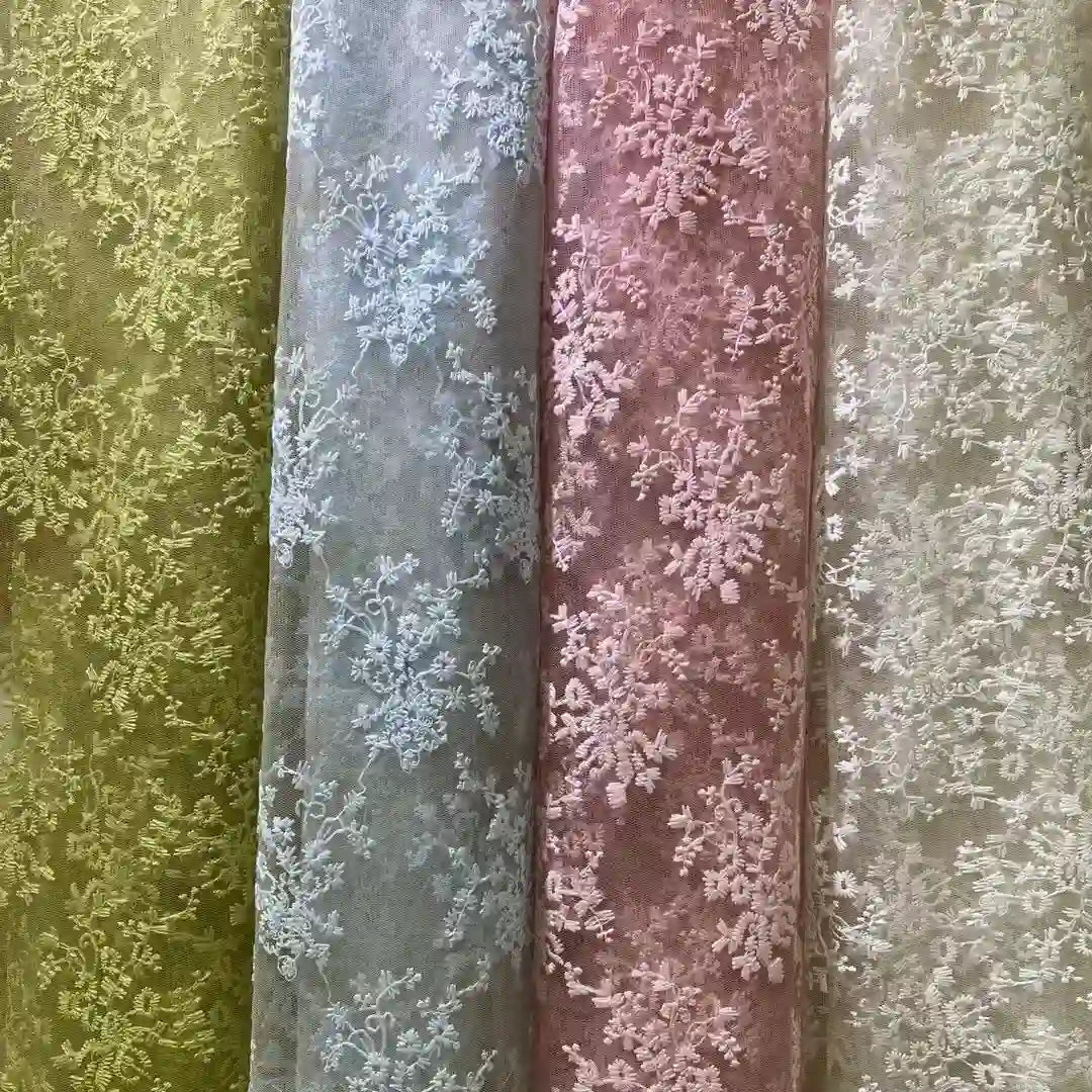 Four rolls of Longan Craft Multicolor Embroidered Floral Tulle Fabric are shown in pastel green, blue, pink, and beige—each with intricate cotton thread embroidery—ideal for wedding lace or elegant projects.