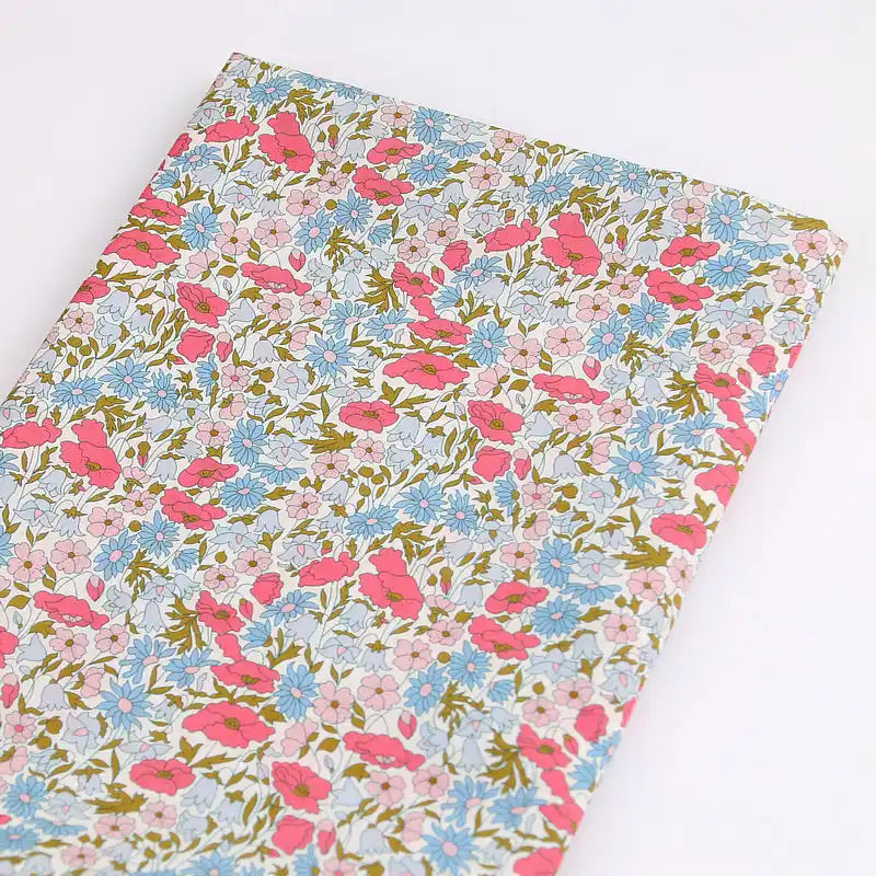 Longan Craft’s Multicolor Fine Cotton Printed Lawn Fabric By The Yard features a lightweight floral print in pink, blue, and white with green leaves on a light background—perfect for breezy summer clothing projects.
