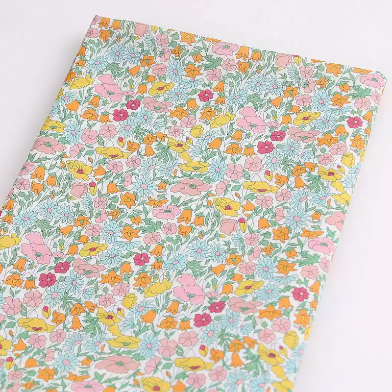 Longan Craft’s Multicolor Fine Cotton Printed Lawn Fabric by the Yard features vibrant pink, yellow, orange, and red flowers with green leaves on white—perfect for creating fresh, lightweight summer clothing.