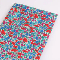 Longan Craft's Multicolor Fine Cotton Printed Lawn Fabric features a vibrant floral print with red, blue, and purple flowers and green leaves on white. Lightweight and ideal for lawn clothing, this material is sold by the yard.