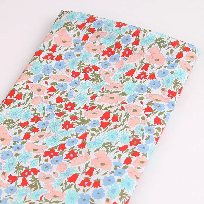 Longan Craft's Multicolor Fine Cotton Printed Lawn Fabric features a lightweight floral print with red, blue, and pink flowers on a light background—perfect for lawn clothing projects. Sold by the yard, neatly folded for your convenience.