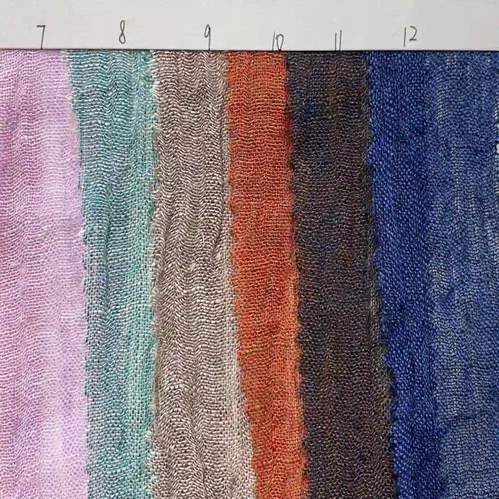 Seven swatches of Longan Craft’s Multicolor Heathered Crepe Fabric By The Yard are arranged side by side, displaying a vibrant assortment of colors and patterns in 100% linen sandwashed crepe. Each swatch is numbered from 7 to 12 above, with every number representing a unique variation of this durable apparel fabric.