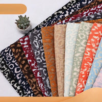 A fan of Multicolor Leopard Chenille Fabric By The Yard swatches in various colors, arranged next to a small potted succulent.