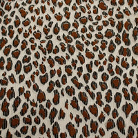 Close-up of Longan Craft's Multicolor Leopard Printed Corduroy Fabric by the yard, featuring irregular black and brown animal spots on soft, light beige polyester corduroy—ideal for apparel.