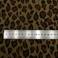 A metal ruler shows centimeter and millimeter scale on Longan Craft's Multicolor Leopard Printed Corduroy Fabric by the Yard, a soft animal print polyester corduroy textile featuring brown, black, and tan patterns for apparel.