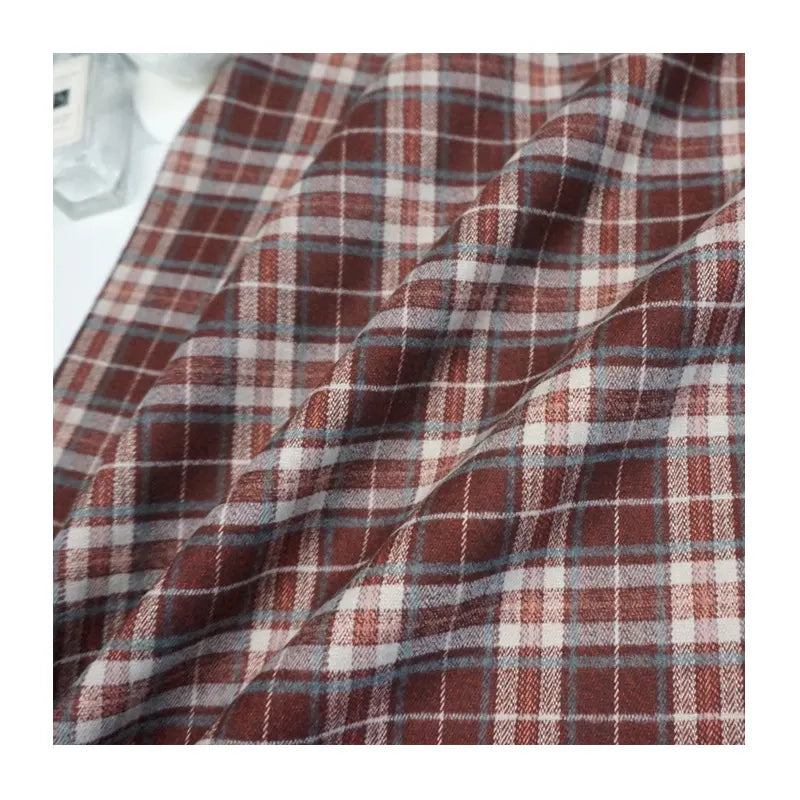 A close-up of Longan Craft's Multicolor Mammoth Flannel Fabric By The Yard shows its red, white, and gray plaid brushed texture—perfect as a cozy textile for pants.