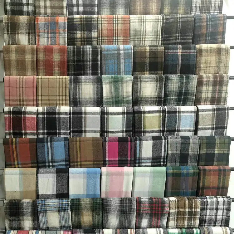 Longan Craft's Multicolor Plaid Mammoth Flannel Fabric by the yard, a brushed polyester cotton textile ideal for shirts, is neatly arranged on display shelves and features a variety of vibrant checkered designs.