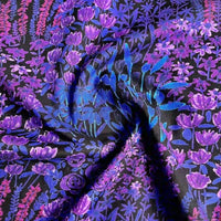 A close-up of Longan Craft's Multicolor Printed Lawn Fabric By The Yard shows vibrant purple, blue, and pink floral patterns on soft cotton lawn cloth material with a dark background. Ideal for sewing and crafts.