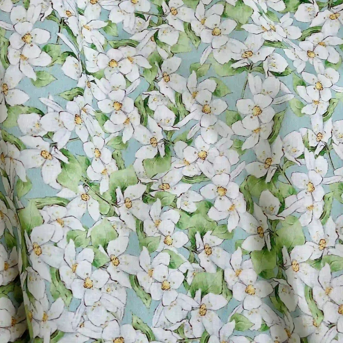 Longan Craft’s Multicolor Printed Lawn Fabric features soft cotton with dense white florals and green leaves on a light blue base, creating a fresh, spring-like look perfect for charming, airy projects.
