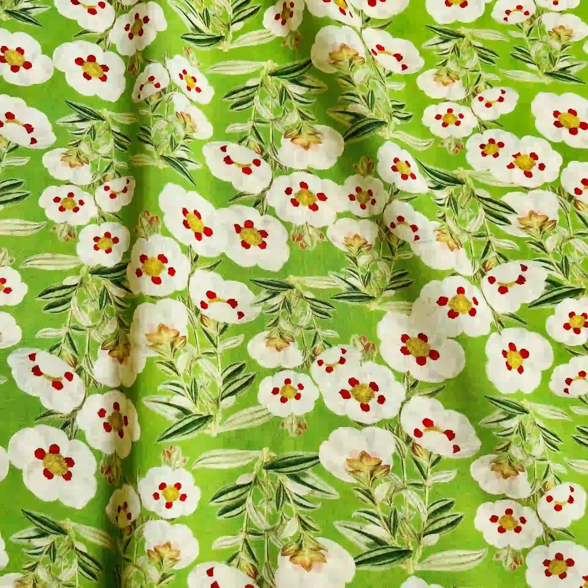 Longan Craft’s Multicolor Printed Lawn Fabric by the yard is a soft cotton lawn with a bright green base, featuring white flowers with red and yellow centers plus leafy green stems, adding gentle folds for texture.