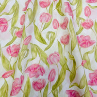 The Longan Craft Multicolor Printed Lawn Fabric features a soft floral cotton lawn design with pink tulips and green leaves on white, ideal for dressmaking or charming fabric projects.