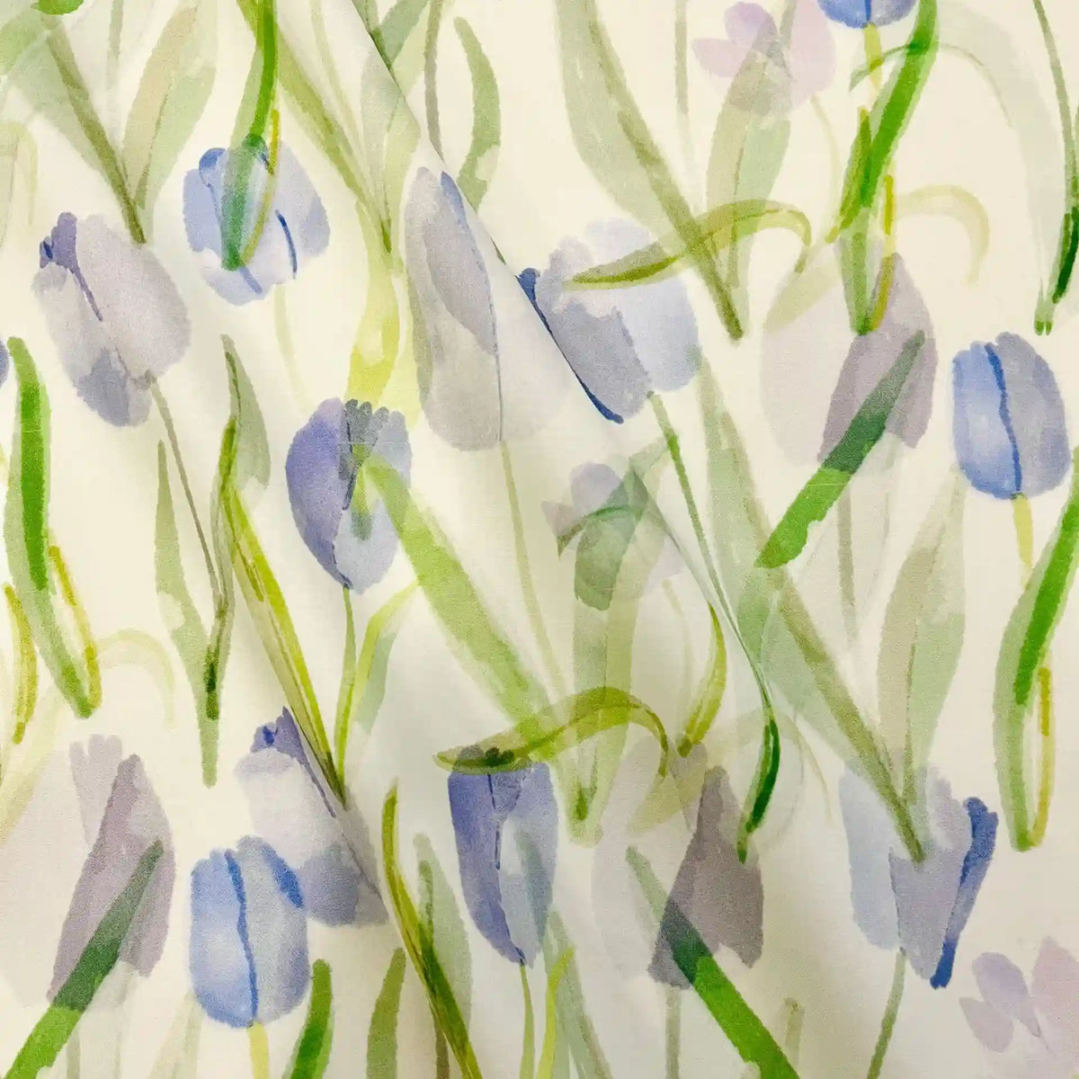 The Longan Craft Multicolor Printed Lawn Fabric by the yard features soft watercolor-style purple and blue tulips with green stems on white cotton, creating a gentle and airy floral design in this premium lawn cloth material.