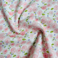 A close-up of Longan Craft's Multicolor Printed Lawn Fabric by the Yard shows soft cotton lawn with pink roses, small purple flowers, and green leaves printed on a white background. Perfect floral cloth material for your projects.