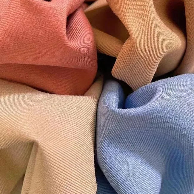 A close-up of Longan Craft’s Multicolor Rayon Gabardine Fabric By The Yard highlights its pastel peach, beige, light blue, and tan hues, soft texture, and fine ribbed pattern—ideal for custom uniforms and versatile projects.