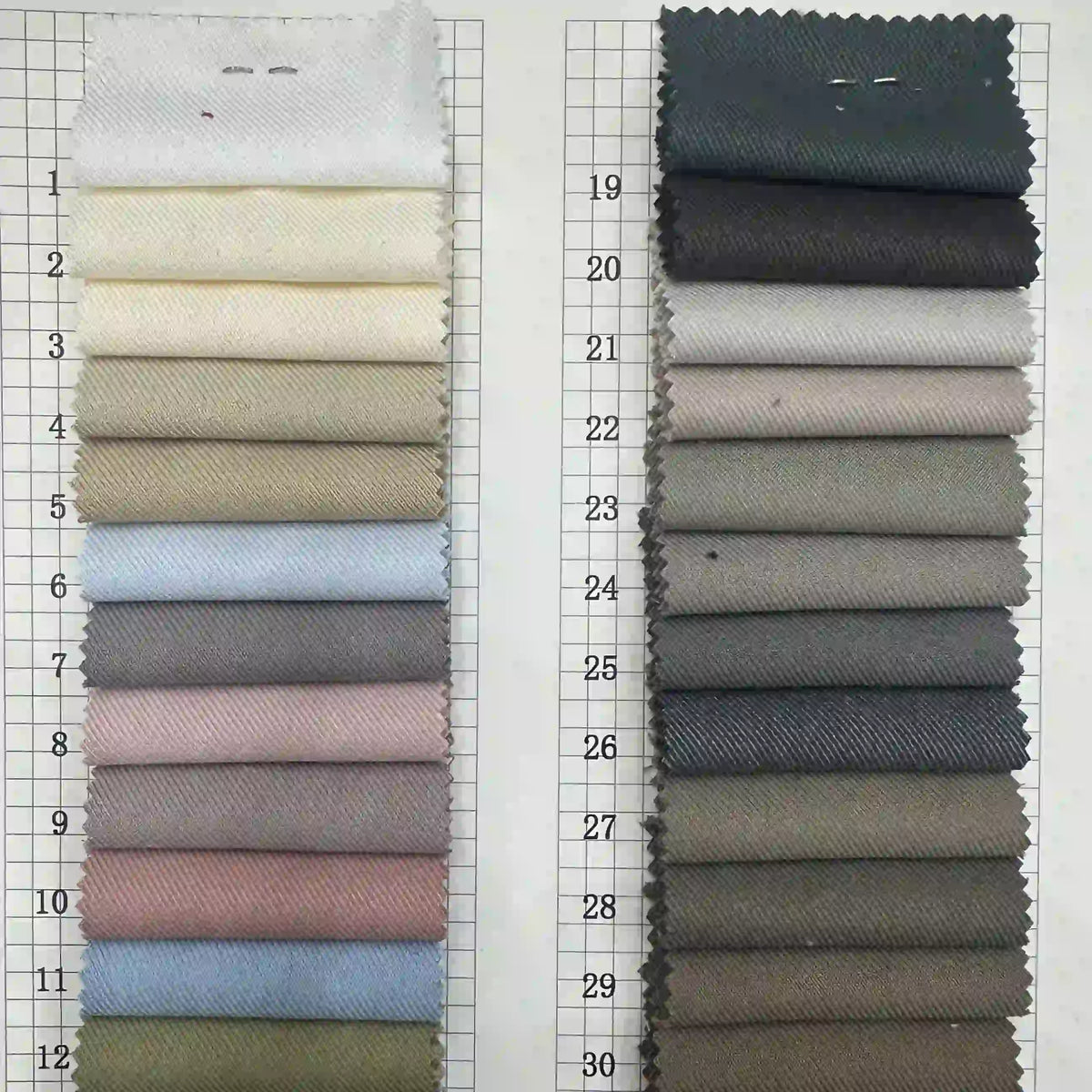 Two columns of Longan Craft Multicolor Rayon Gabardine swatches, each solid color, are numbered 1–12 (left) and 19–30 (right), arranged light to dark on a grid. Stretch viscose twill gabardine fabric—ideal for custom uniforms.