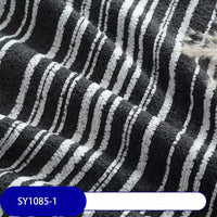 Close-up of thick black poly chenille fabric with white and gray horizontal stripes and wavy folds. A blue label shows SY1085-1. Longan Craft’s Multicolor Striped Chenille Fabric By The Yard is perfect for upholstery or decor projects.