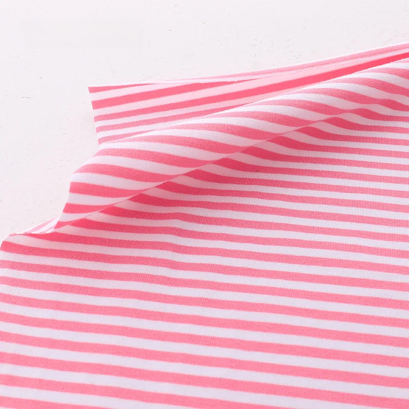 A piece of Longan Craft Multicolor Striped Cotton Jersey Fabric by the yard, with stretch elastane and sports jersey texture, lies on a white surface, one corner slightly lifted to display its flexibility.