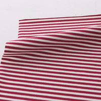 A slightly wrinkled piece of Longan Craft Multicolor Striped Cotton Jersey Fabric by the yard, featuring stretch elastane for sportswear, lies on a white surface.