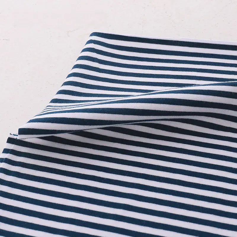 A close-up of Longan Craft Multicolor Striped Cotton Jersey Fabric By The Yard, a stretch elastane sports jersey material with navy and white horizontal stripes on a light background.