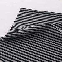 A piece of Longan Craft Multicolor Striped Cotton Jersey Fabric By The Yard is displayed on a white surface, with black and gray stripes visible and part gently folded to showcase its soft, stretchy sports jersey material.