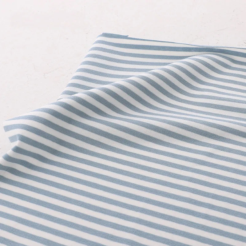 The Longan Craft Multicolor Striped Cotton Jersey Fabric By The Yard features light blue and white stripes on soft, stretchy elastane jersey—perfect for comfortable sportswear and activewear projects.