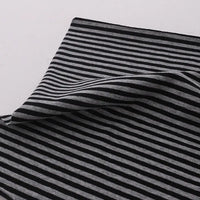 A close-up of Multicolor Striped Cotton Jersey Fabric By The Yard from Longan Craft, featuring stretch elastane jersey material in black and gray stripes with a folded corner, showcasing the sports jersey fabric's texture on a white background.