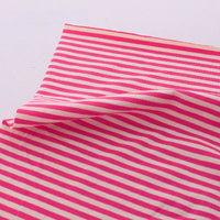 The Longan Craft Multicolor Striped Cotton Jersey Fabric by the Yard, featuring pink and white diagonal stripes, is shown lying flat with one corner slightly lifted—ideal stretchy elastane sports jersey material.
