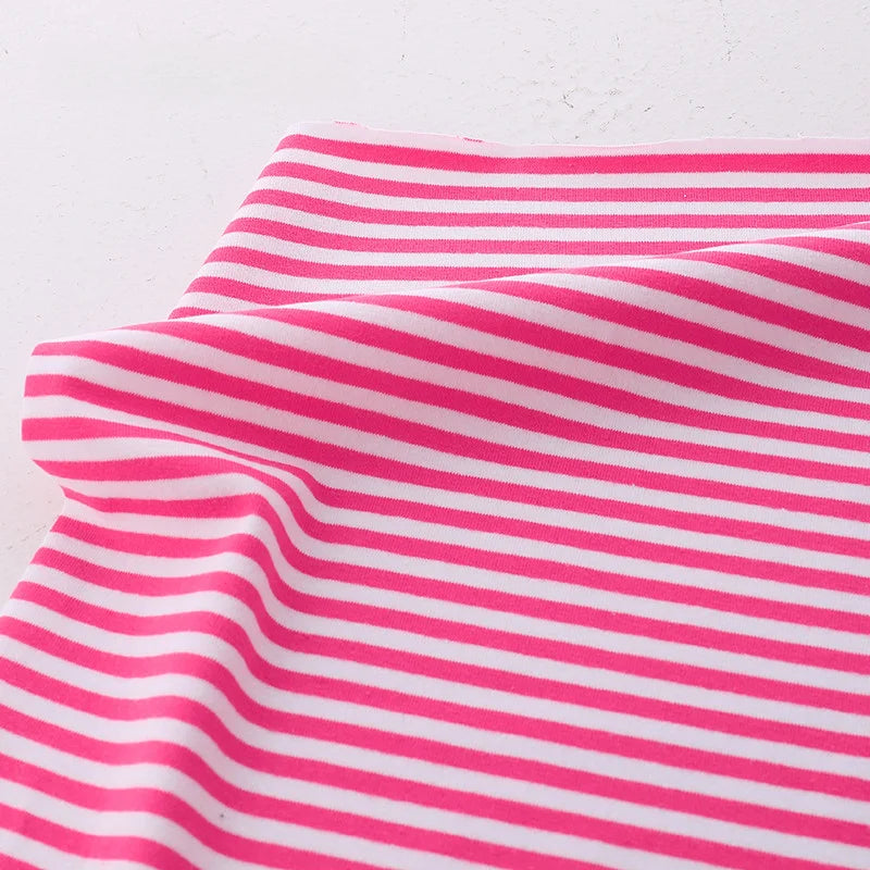 The Longan Craft Multicolor Striped Cotton Jersey Fabric By The Yard, a stretch elastane sports jersey material, features pink and white horizontal stripes with gentle folds on a white surface.