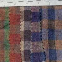 Three strips of Longan Craft’s Multicolor Washed Plaid Linen Fabric By The Yard, featuring vintage checkered patterns in red, blue, and brown tones, are displayed side by side. A ruler at the top indicates measurements ranging from 7 to 12 centimeters, and the fabric’s edges showcase a zigzag finish.
