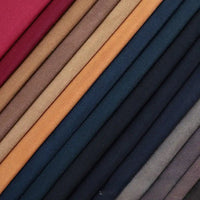 A close-up of neatly stacked Longan Craft Multicolor Waxed Cotton Canvas Fabric by the yard in red, brown, tan, navy blue, and gray—100% cotton waterproof material perfect for outdoor clothing—arranged diagonally.