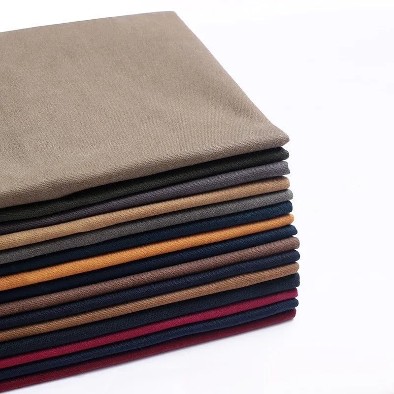 A stack of folded Longan Craft Multicolor Waxed Cotton Canvas Fabric features brown, navy blue, mustard yellow, maroon, and burgundy waterproof cotton fabric by the yard, perfect for outdoor clothing, set against a white background.