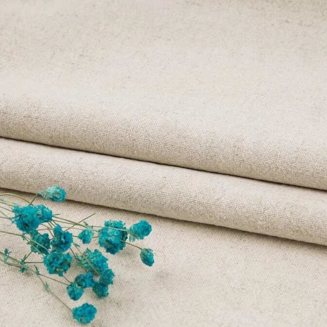 A close-up of Longan Craft Multiple Colors Linen Fabric By The Yard, a washable cotton linen blend for apparel, shown in beige layers with turquoise dried flowers on top. Durable and breathable clothing material.