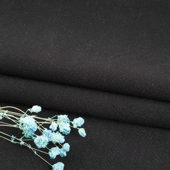 A close-up of Longan Craft's Multiple Colors Linen Fabric By The Yard, a durable washed cotton linen blend for apparel, with light blue dried flowers resting on the breathable material.