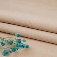 A sprig of small dried blue flowers rests on three neatly folded pieces of Longan Craft Multiple Colors Washed Cotton Linen Blend Fabric, each showcasing the durable, breathable texture ideal for apparel.