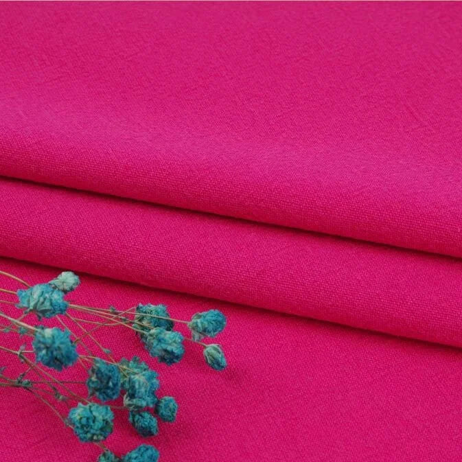 A close-up of bright pink Multiple Colors Linen Fabric By The Yard from Longan Craft, a washed cotton linen blend known for its softness, durability, and breathable natural fibers—shown here with dried blue flowers on top.