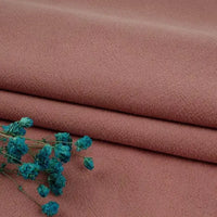 Longan Craft Multiple Colors Linen Fabric By The Yard, a washed cotton linen blend for apparel, shown in soft mauve or dusty pink with delicate blue dried flowers on the lower left. Durable and perfect for clothing projects.