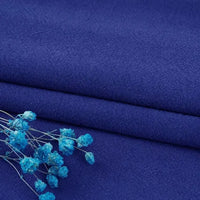 A close-up of two folded pieces of Longan Craft Multiple Colors Linen Fabric By The Yard in deep blue, accented with small dried blue flowers for an elegant, soft look. Durable washed cotton linen blend, perfect for apparel.