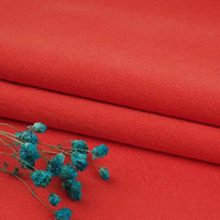 Two pieces of bright red Multiple Colors Linen Fabric By The Yard from Longan Craft are stacked neatly, with small blue dried flowers on top, creating a vivid contrast on the durable washed cotton linen blend material for apparel.